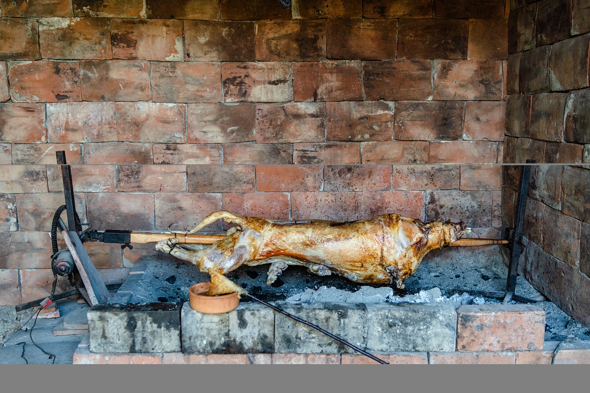 Close up on roasted lamb on the spit impaled skewer cooked in traditional balkan cuisine grilled using hot charcoal