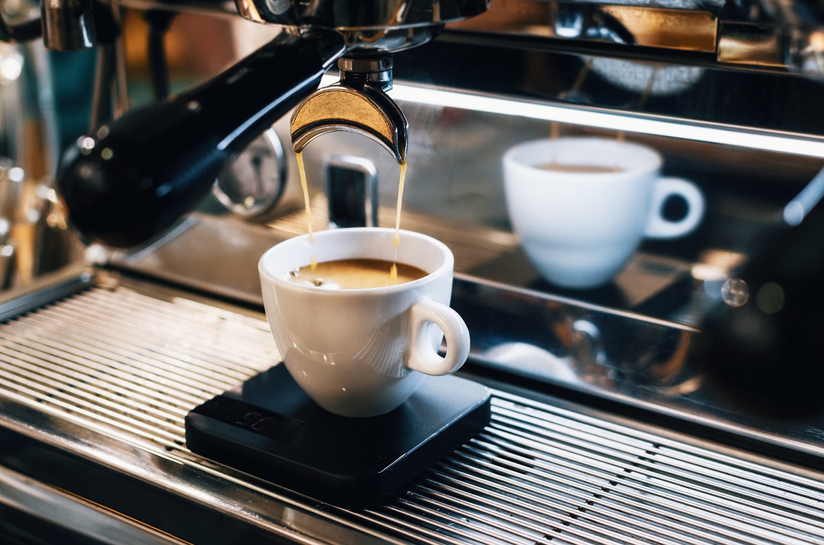 Espresso machine pouring coffee into white cup