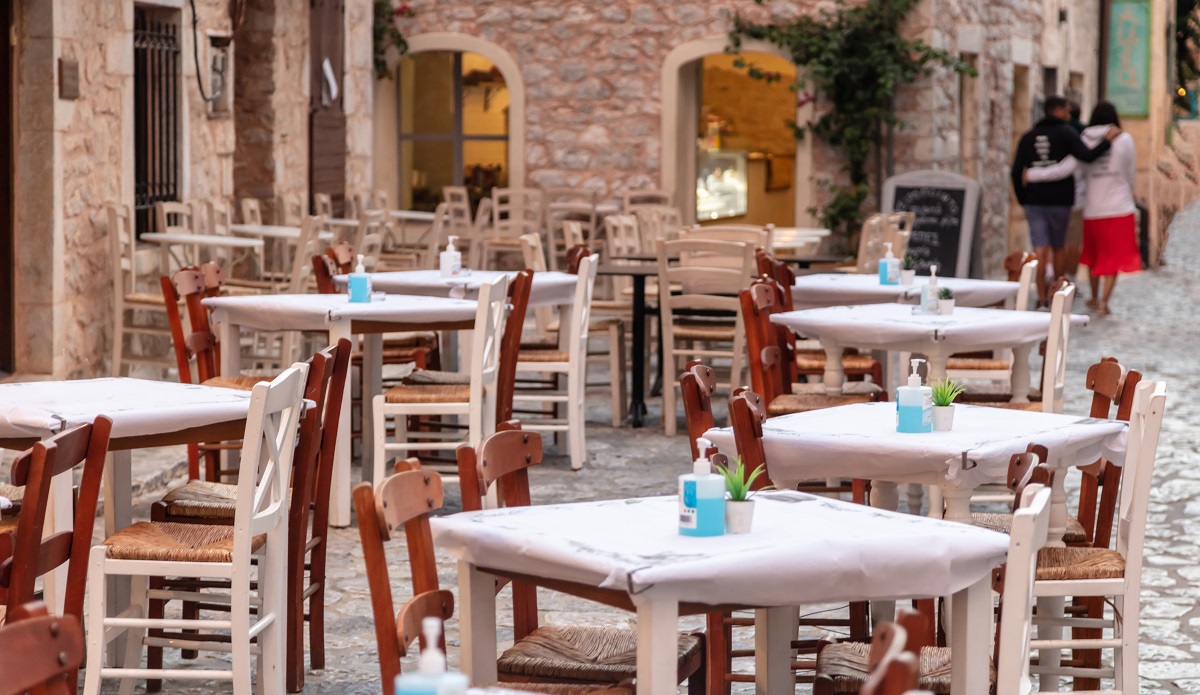 Greek tavern outdoor empty seats on cobblestone street, stone wall background, Areopoli, Mani Greece