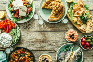 Selection of traditional greek food – salad, meze, pie, fish, tzatziki, dolma on wood background