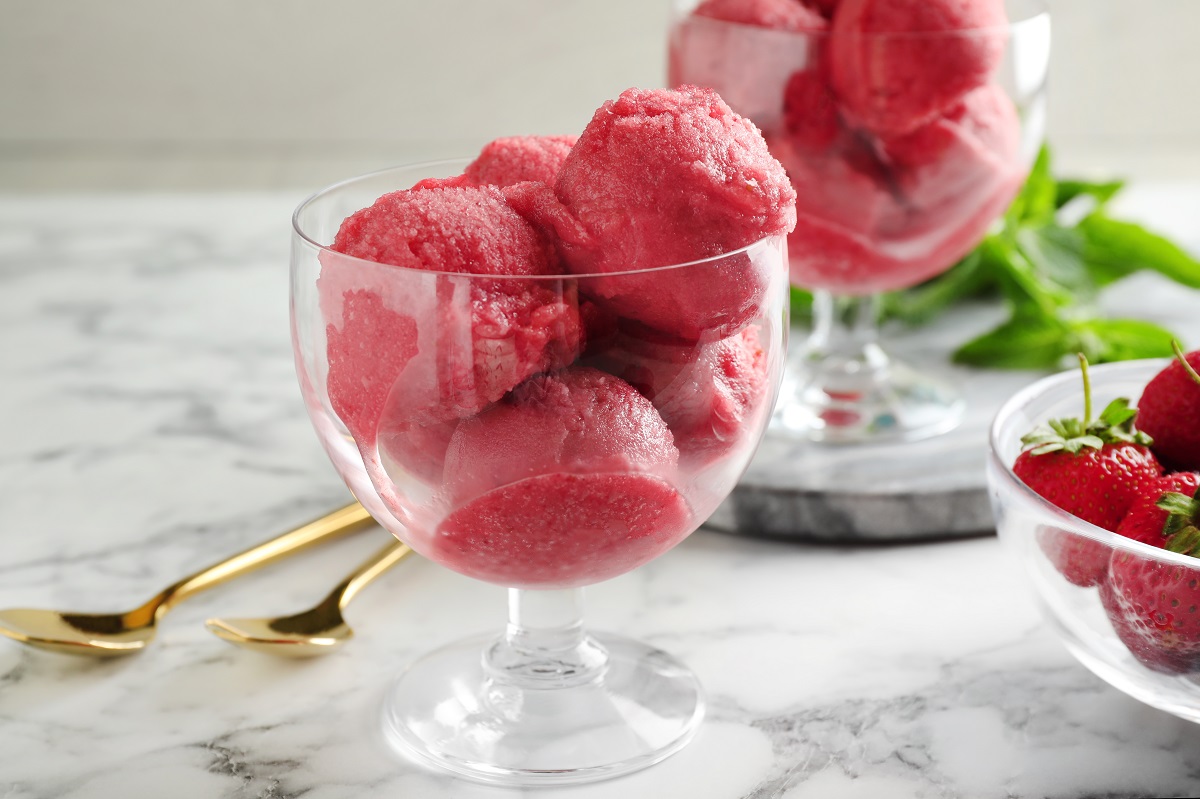 Delicious pink ice cream served with strawberries on marble table