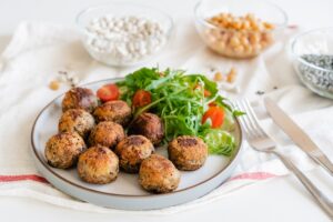 Vegan veggie meatballs on the plate with fresh salad. Plant based pea protein ingredients on the background. Vegetarian lunch. Healthy eating concept. Go vegan. Selective focus, copy space