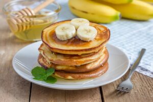 Stack of pancakes with banana and honey