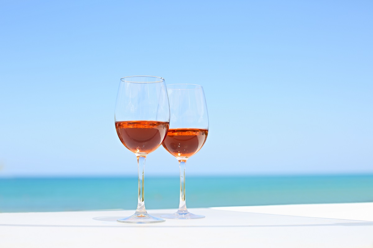 Two glasses of rose wine against blue water and sea