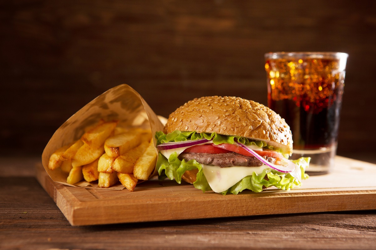 american snack with big burger and glass cola on wooden table Delicious fast food.