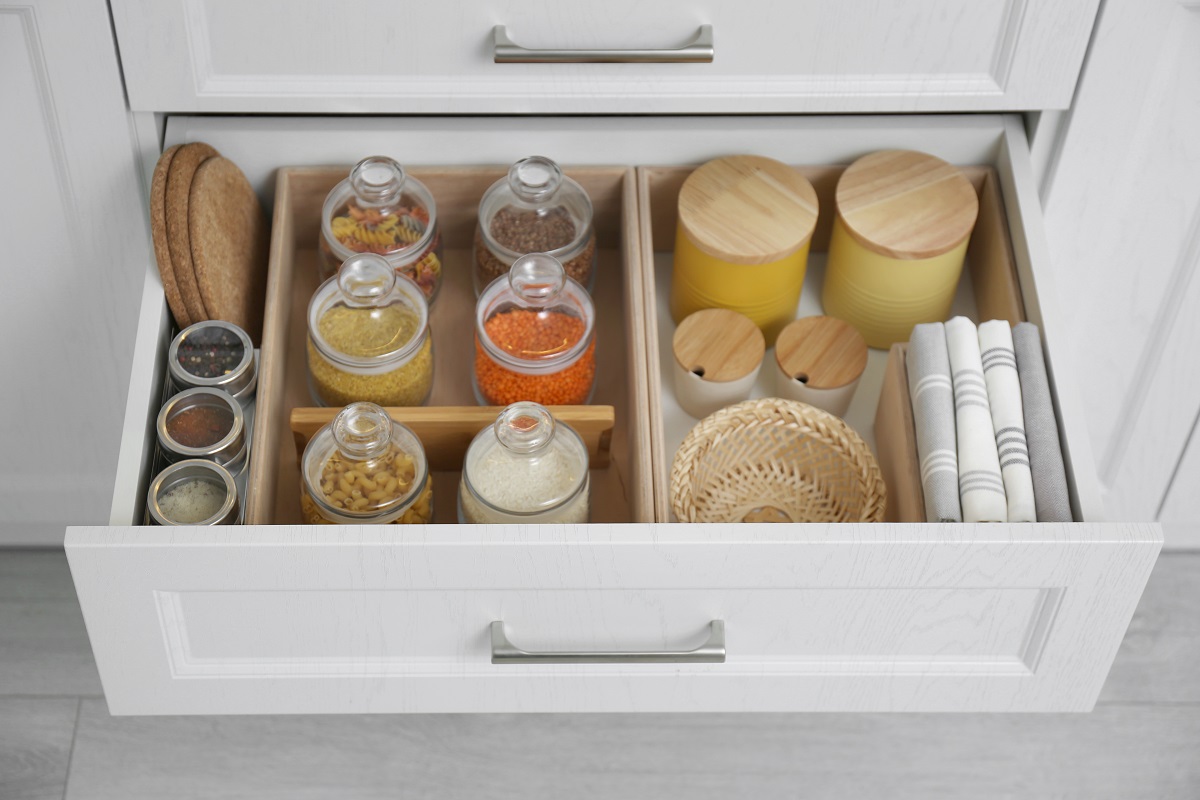 Open drawer with different jars indoors. Order in kitchen