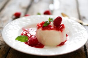Delicious italian dessert panna cotta with raspberry sauce and m