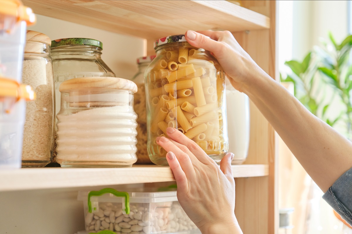 Food products in the kitchen. Woman taking jar of pasta