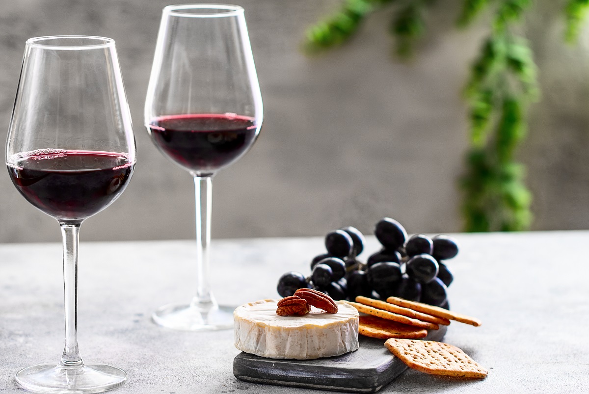Two,Red,Wine,Glasses,And,Cutting,Board,With,Dgrapes,cheese,And