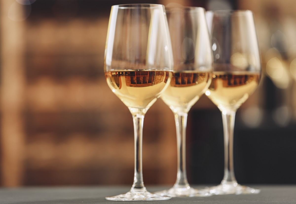 Glasses,With,White,Wine,On,Blurred,Background