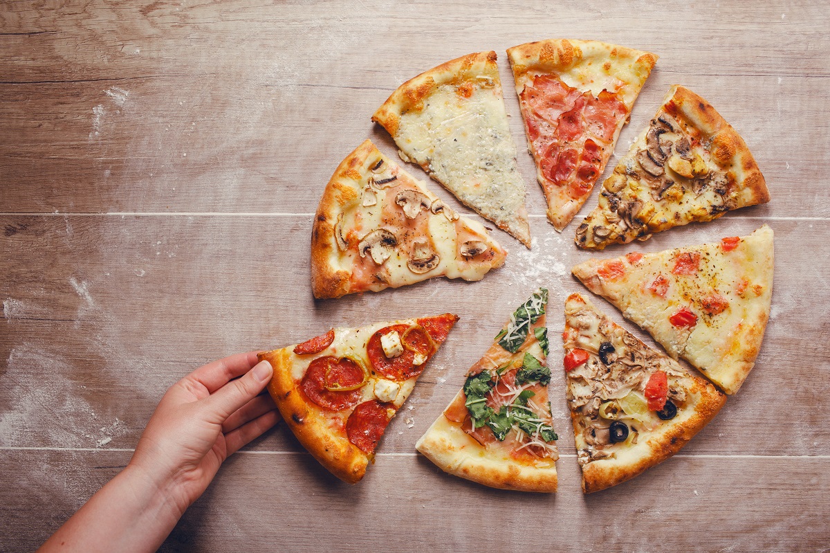 Slices,Of,Pizza,With,Different,Toppings,On,A,Wooden,Background