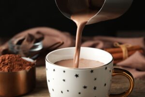 Pouring,Hot,Cocoa,Drink,Into,Cup,On,Wooden,Table