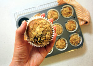 Hand,Holding,Onto,A,Muffins,With,Muesli,Crumb,On,Top