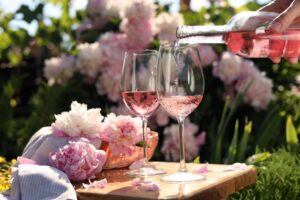 Woman,Pouring,Rose,Wine,Into,Glass,At,Table,In,Garden,