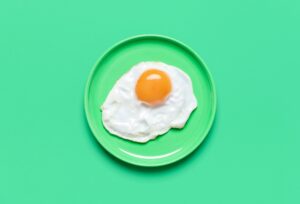 Single,Fried,Egg,In,A,Plate,Minimalist,On,A,Green