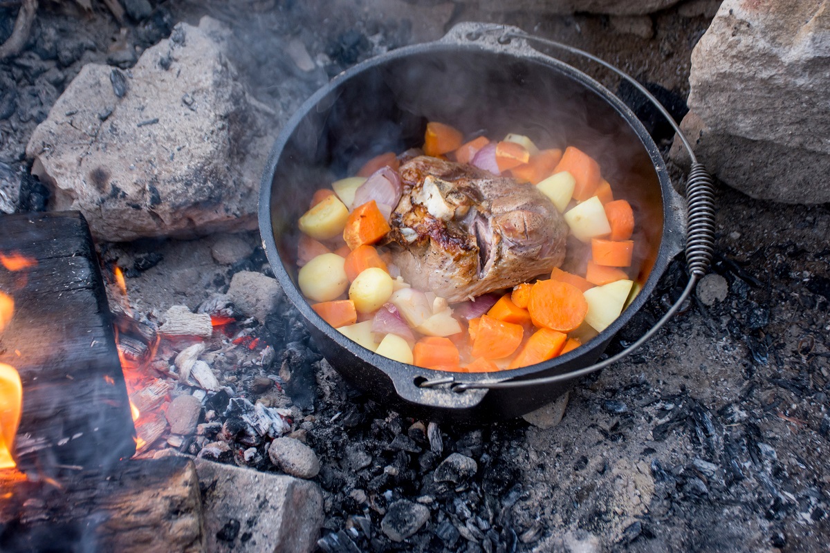 Dutch oven campfire cooking process – lamb and vegetables in a cast iron camp oven, Camping life