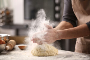 Male,Hands,Clapping,And,Sprinkling,White,Flour,Over,Dough,On
