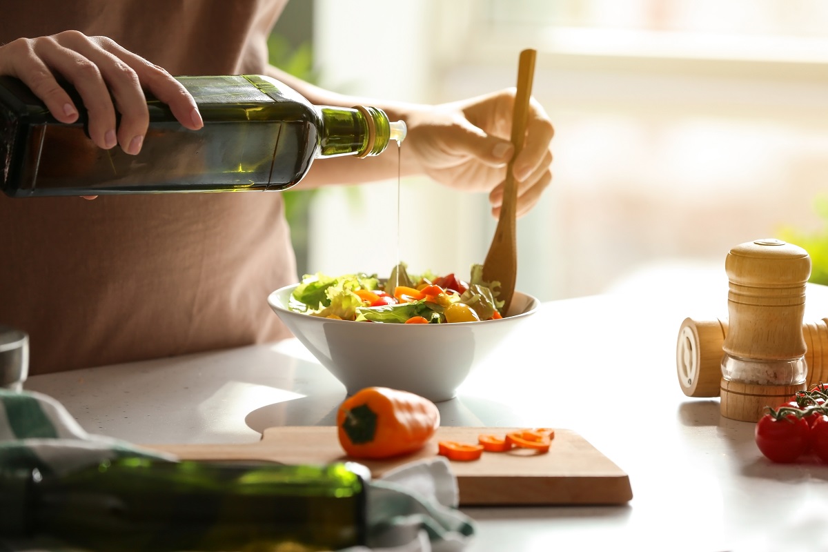 Woman,Adding,Olive,Oil,Into,Bowl,With,Fresh,Vegetable,Salad