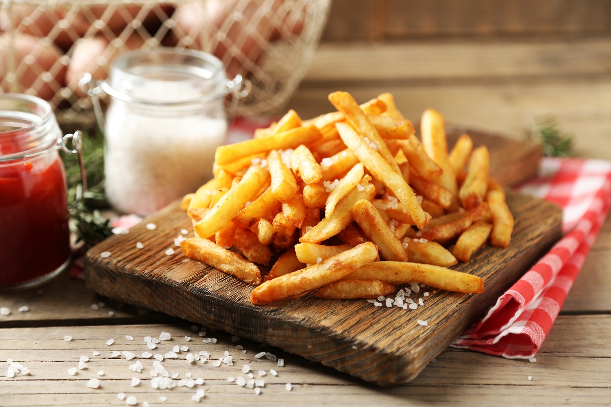 Tasty,French,Fries,On,Cutting,Board,,On,Wooden,Table,Background