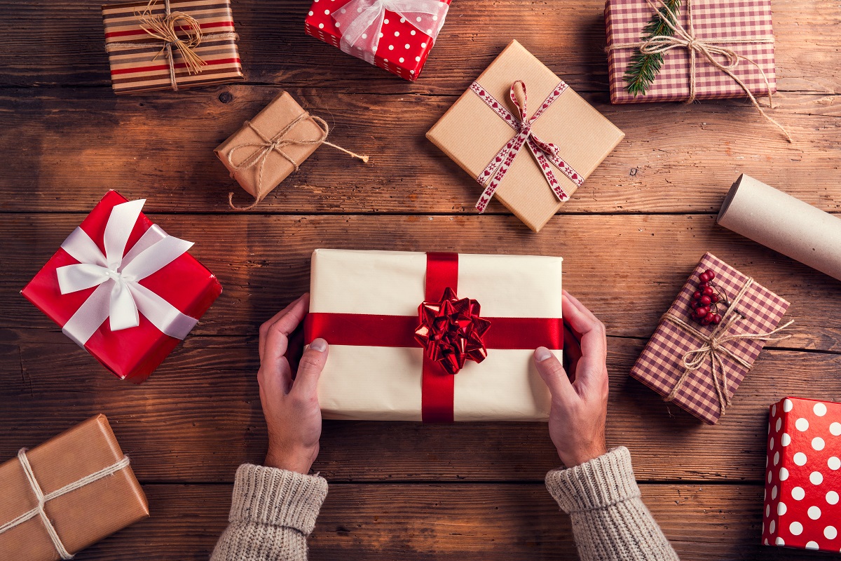 Man,Holding,Christmas,Presents,Laid,On,A,Wooden,Table,Background