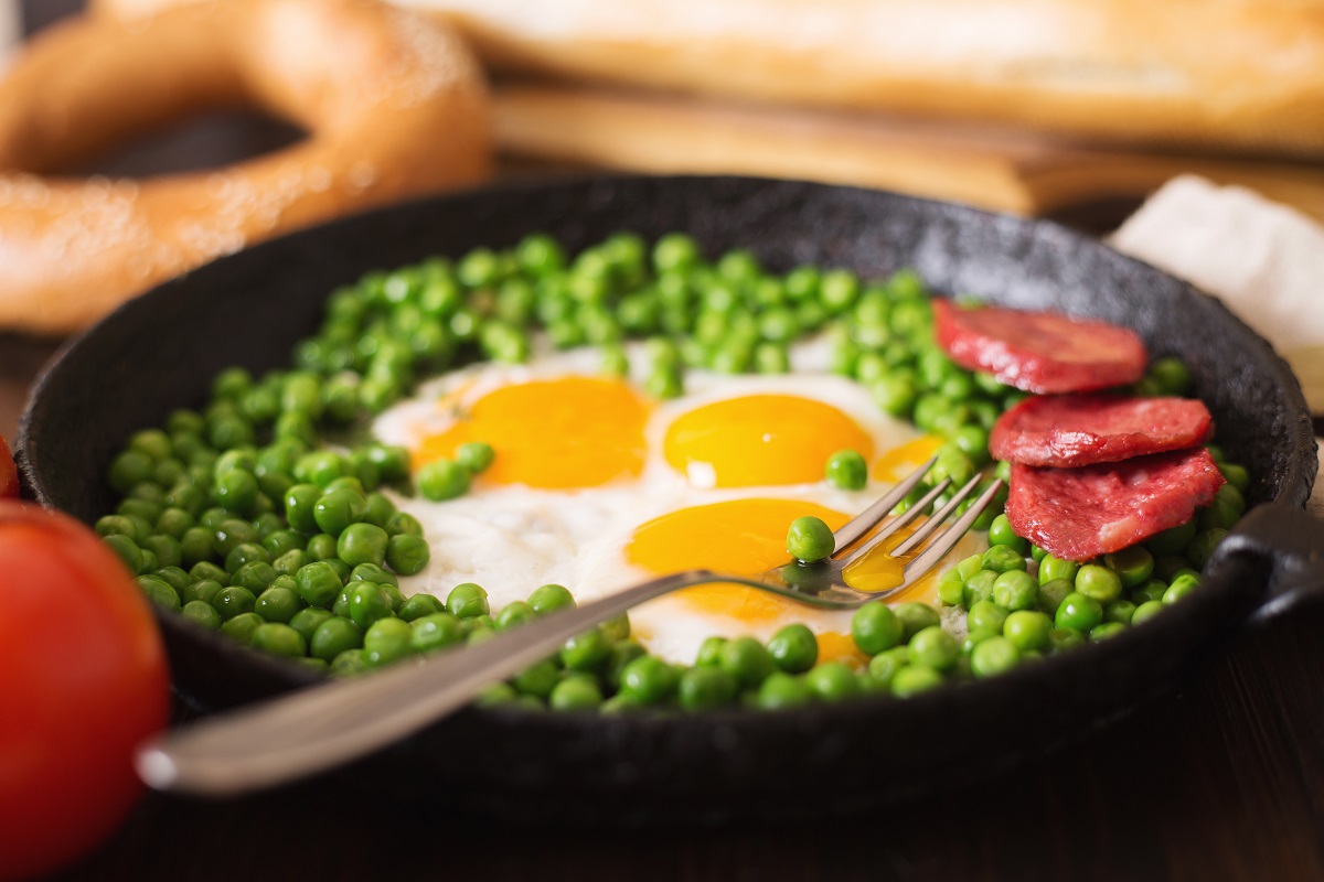 Fried,Eggs,With,Sausage,And,Green,Peas,On,A,Black