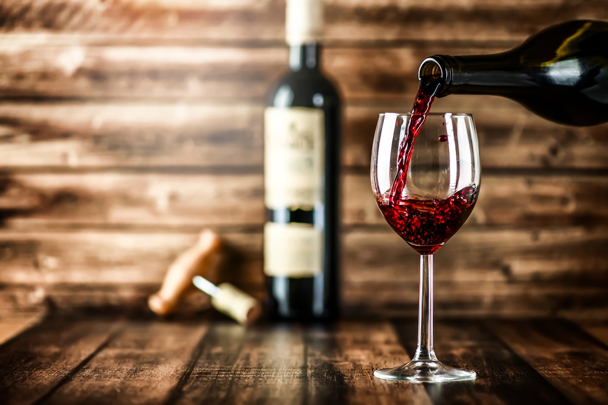 Pouring,Red,Wine,Into,The,Glass,Against,Rustic,Background.