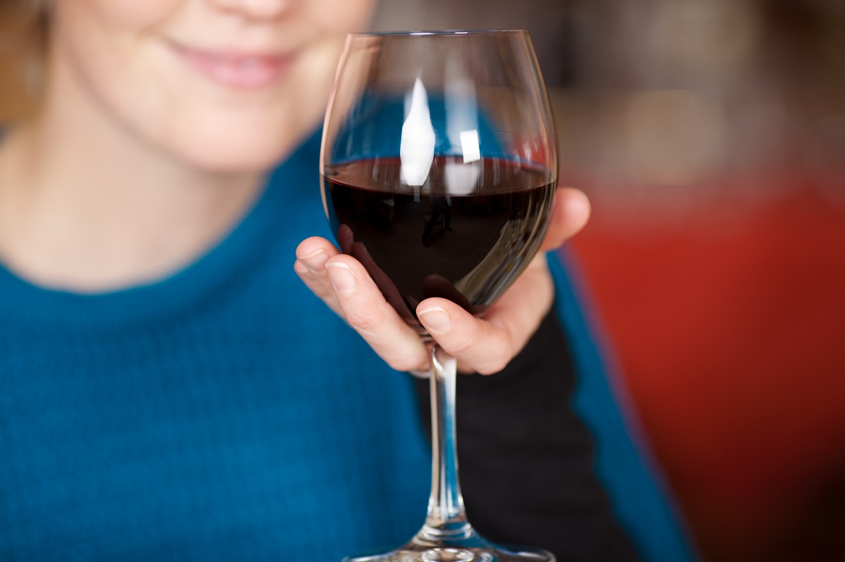 Young,Woman,Holding,Red,Wine,Glass,At,Restaurant