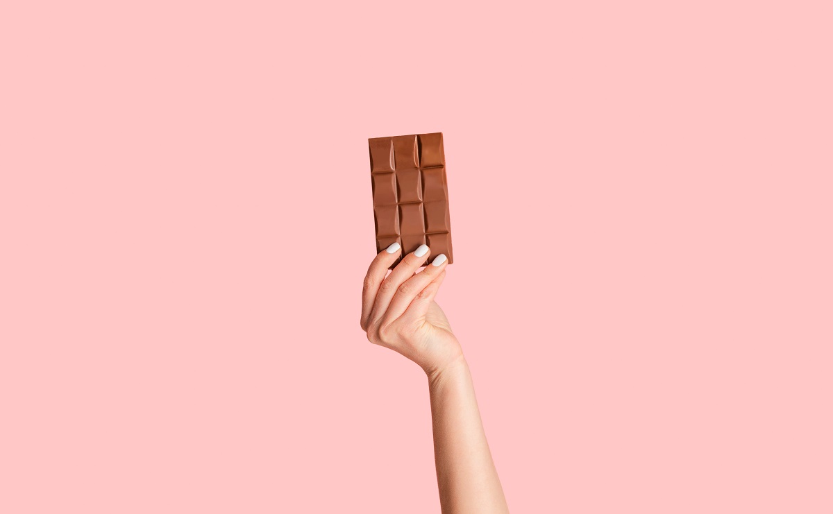 Millennial,Woman,Holding,Bar,Of,Organic,Chocolate,Over,Pink,Background,