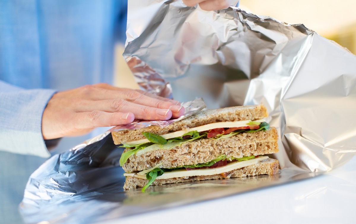 Close,Up,Of,Woman,Wrapping,Sandwich,In,Non,Reusable,Aluminium