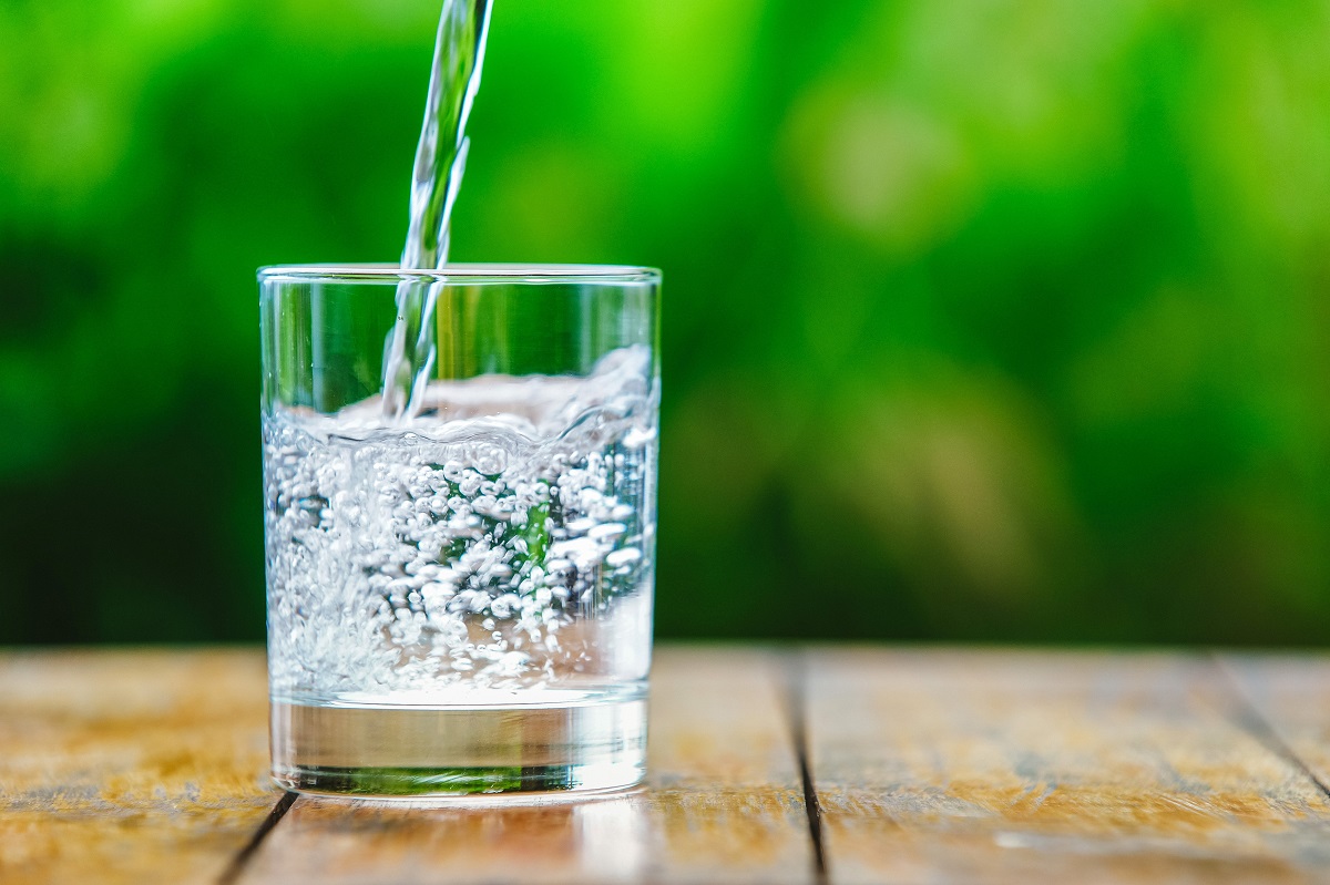 A,Glass,Of,Water,On,Green,Background.,The,Wooden,Table.