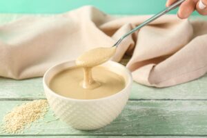 Female,Hand,With,Bowl,And,Spoon,Of,Tasty,Tahini,On